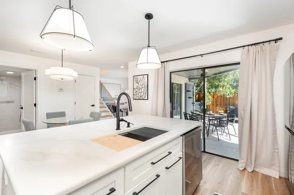 a kitchen with a sink chandelier and living room view