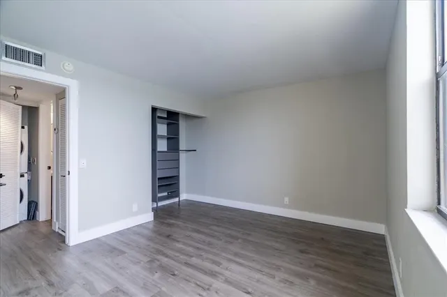 a view of an empty room with wooden floor and closet