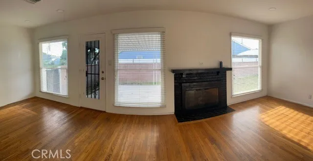 an empty room with wooden floor cabinet and windows