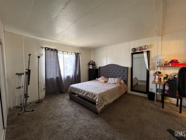 a spacious bedroom with a bed and a refrigerator