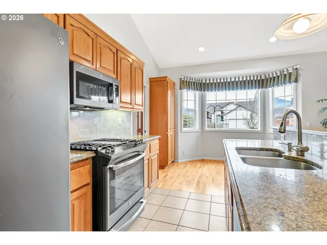 a kitchen with stainless steel appliances granite countertop a stove a sink and a microwave