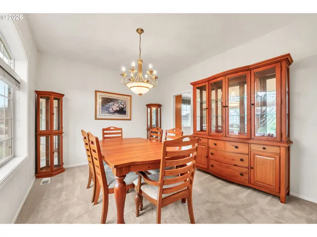 a view of a dining room with furniture a chandelier and large windows
