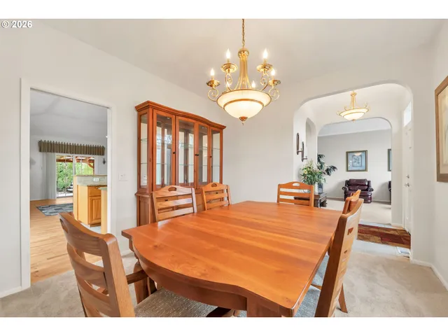 a dining room with wooden floor a chandelier a wooden table and chairs