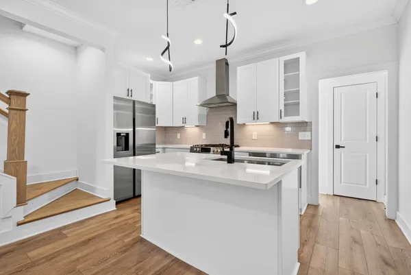 a kitchen with stainless steel appliances granite countertop a sink a stove a refrigerator and island with wooden floor