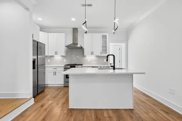 a kitchen with stainless steel appliances a sink stove and wooden floor
