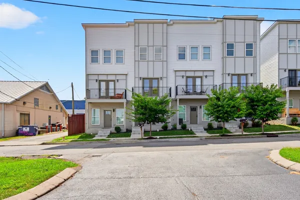 a front view of a building with a garden and plants