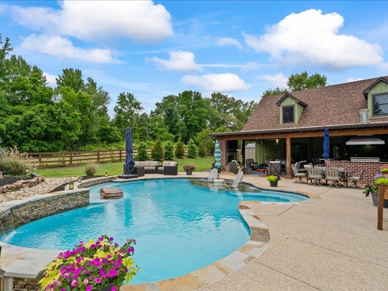 a view of a swimming pool with outdoor seating and a garden