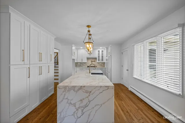 a kitchen with kitchen island granite countertop a sink a stove and white cabinets