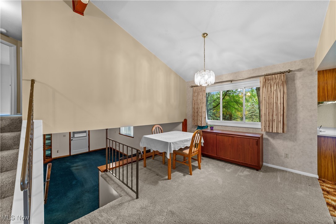 648 Rehwinkle Road Northfield, OH 44067 - Photo 11 of 38 Dining area with stairs, dark colored carpet, vaulted ceiling, and a chandelier