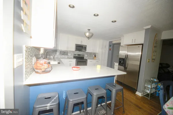 a kitchen with stainless steel appliances granite countertop a sink a stove a refrigerator and island with wooden floor