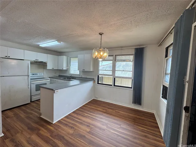 a kitchen with stainless steel appliances granite countertop a refrigerator a sink dishwasher a stove and white countertops with wooden floor