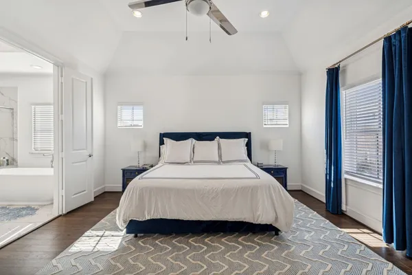 a bedroom with a bed and a walk in closet with wooden floor