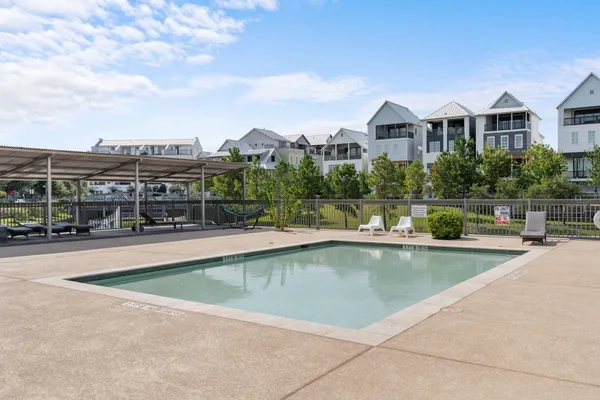 a view of a swimming pool and a chairs in front of house