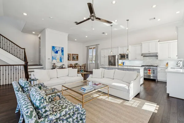a living room with furniture kitchen view and a chandelier