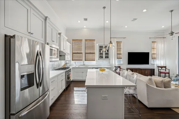 a large kitchen with stainless steel appliances kitchen island granite countertop a refrigerator a sink dishwasher a couches and flat screen tv