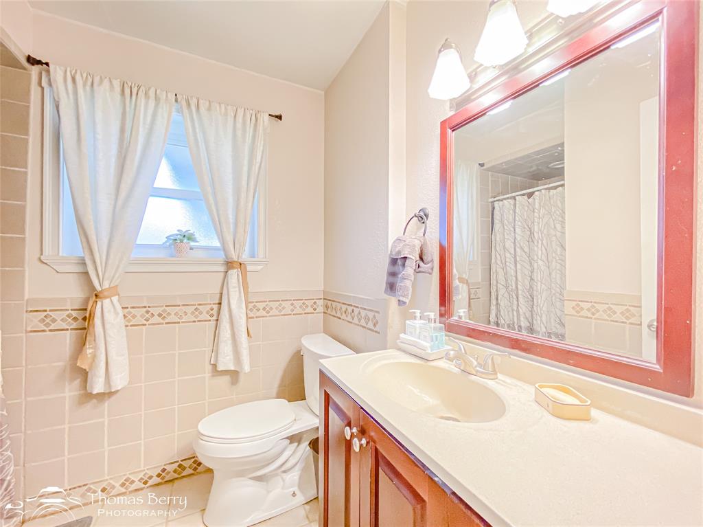 1104 Hickory Street Roscoe, TX 79545 - Photo 17 of 22 Bathroom with a shower with shower curtain, vanity, tile walls, a wainscoted wall, and light tile patterned flooring