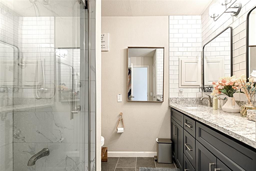 2704 Spring Drive McKinney, TX 75072 - Photo 27 of 35 a bathroom with a granite countertop sink a mirror and a shower