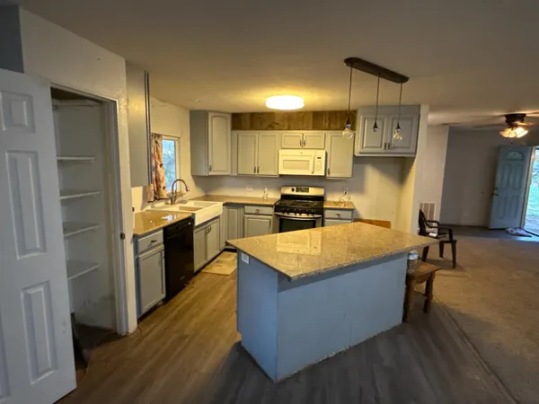 a large kitchen with stainless steel appliances a stove a refrigerator a sink dishwasher and a oven with wooden floor