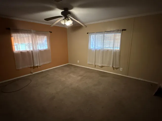 an empty room with chandelier fan and windows