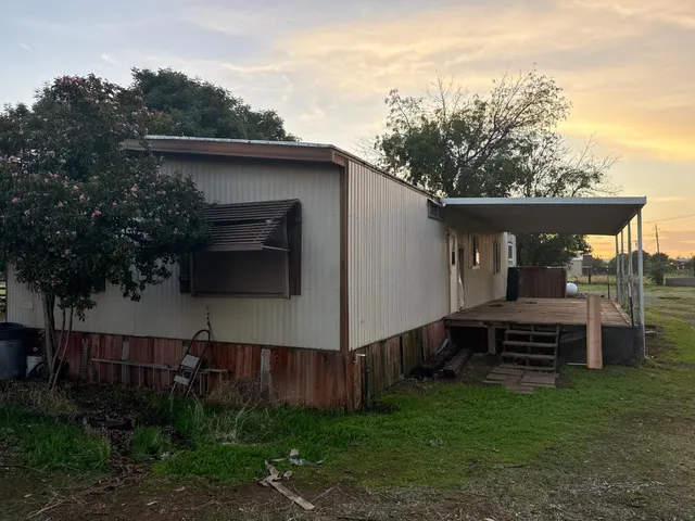 a view of a back yard of the house with a bench
