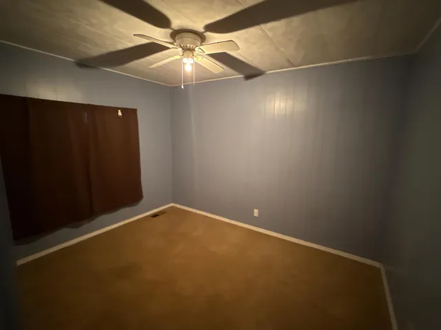 an empty room with a ceiling fan and a window