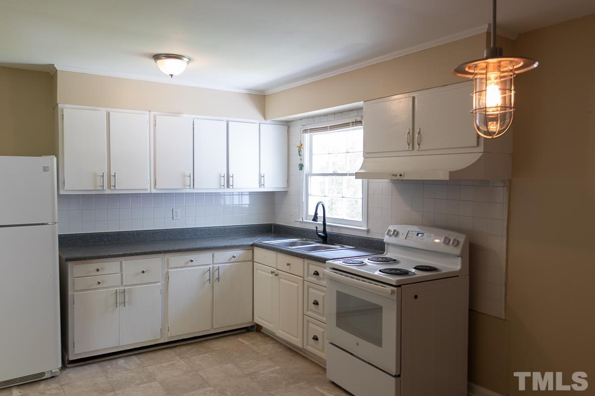 4914 Brentwood Road Durham, NC 27713 - Photo 4 of 11 a kitchen with granite countertop white cabinets and white appliances