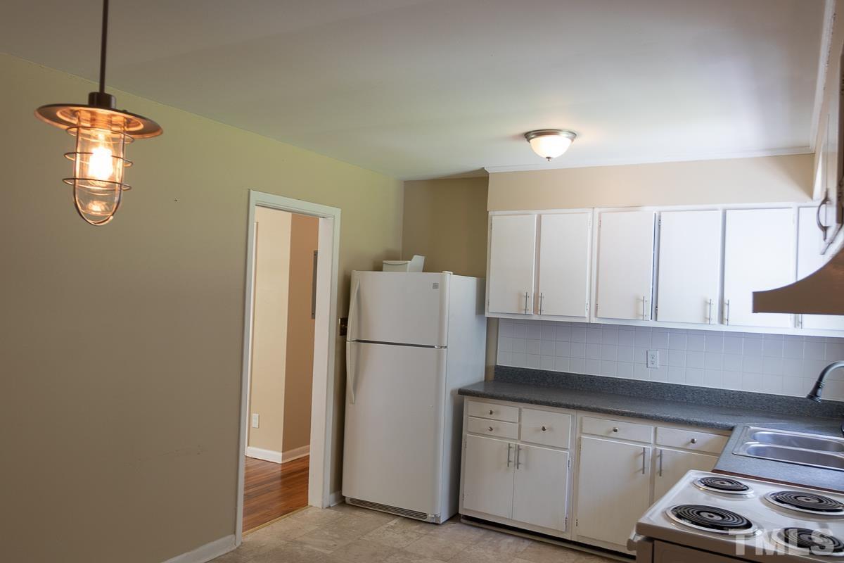 4914 Brentwood Road Durham, NC 27713 - Photo 5 of 11 a kitchen with a refrigerator a stove a sink and a window