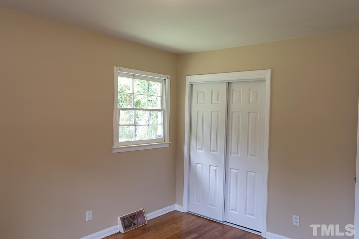 4914 Brentwood Road Durham, NC 27713 - Photo 8 of 11 a view of an empty room with wooden floor and a window