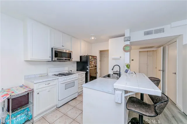 a kitchen with white cabinets stainless steel appliances and dining table