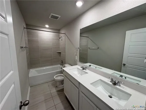 a bathroom with a tub sink mirror and toilet