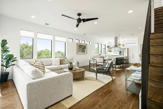 a living room with furniture kitchen view and a large window