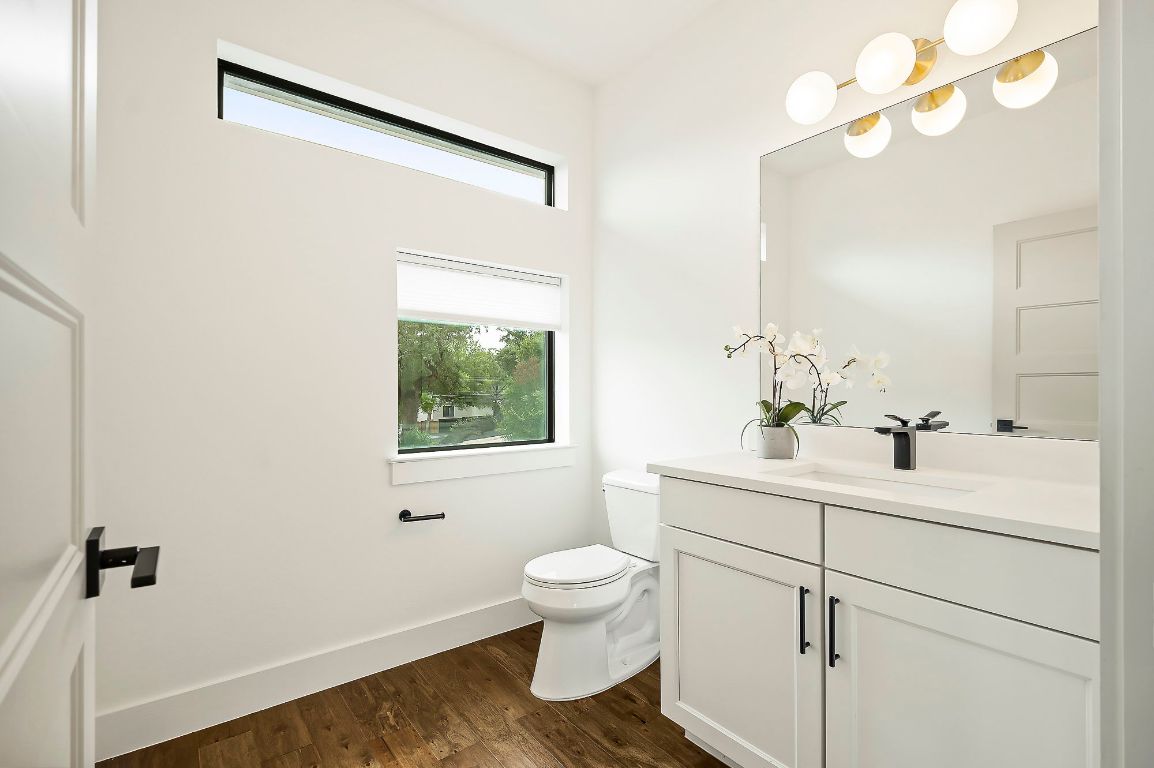 1104 Marcy Street, Unit B Austin, TX 78745 - Photo 18 of 34 a bathroom with a toilet a sink a mirror a vanity and window