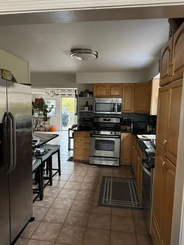 a kitchen with stainless steel appliances kitchen island granite countertop a refrigerator and a stove top oven