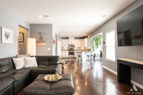 a kitchen with stainless steel appliances kitchen island granite countertop a refrigerator a stove a sink a dining table and chairs with wooden floor