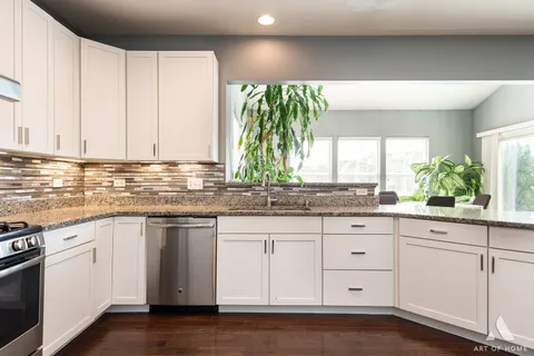 a kitchen with stainless steel appliances a dining table chairs and refrigerator