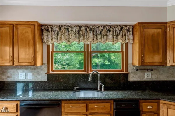 a kitchen with granite countertop a sink and wooden cabinets