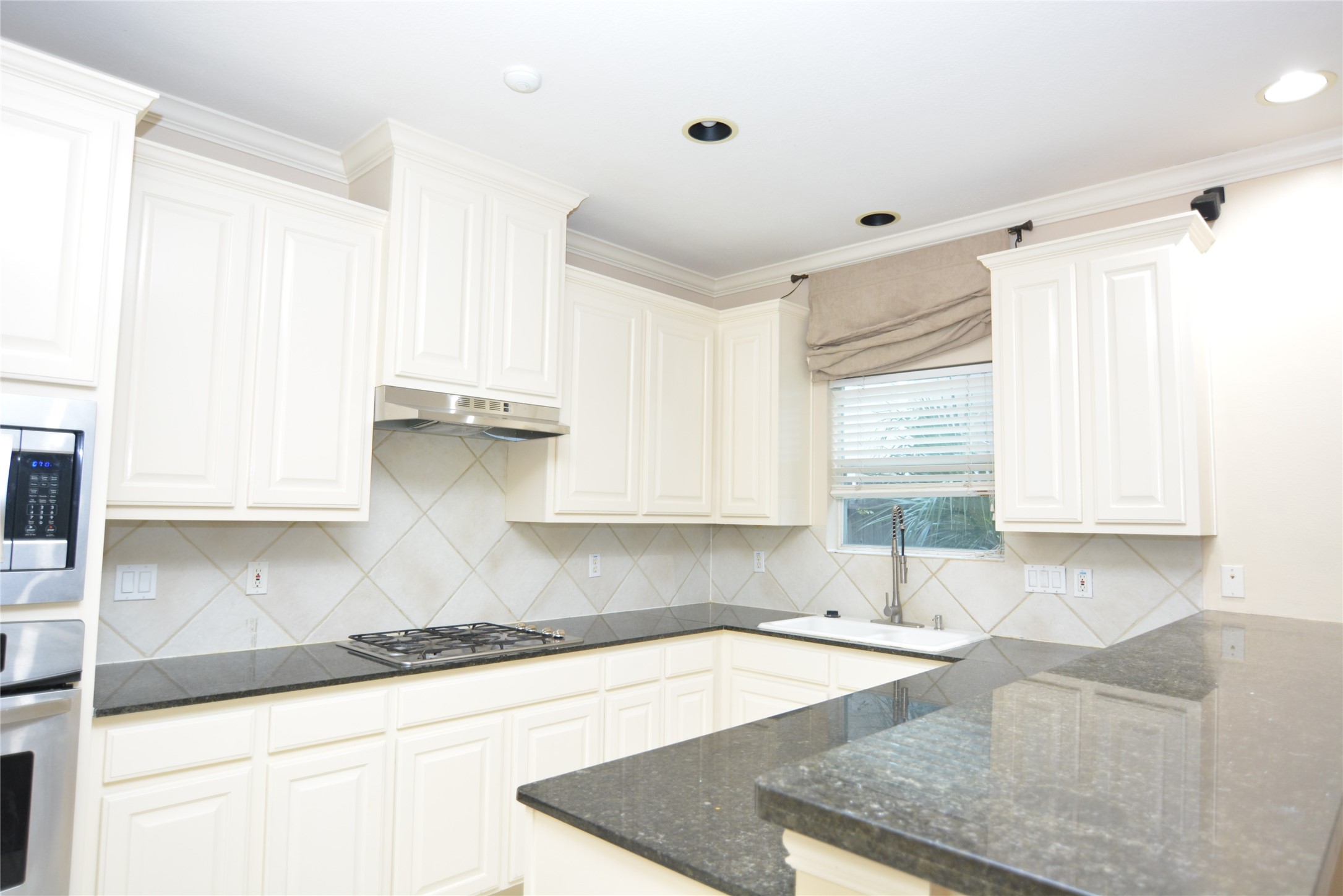 6119 Windwater Pointe Houston, TX 77036 - Photo 6 of 23 a kitchen with granite countertop a sink window and cabinets
