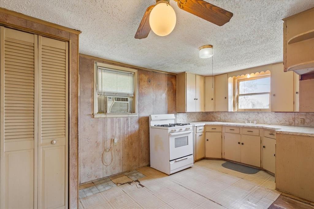 100 County Road 120 C Riesel, TX 76682 - Photo 9 of 25 Kitchen featuring light countertops, white gas range, healthy amount of natural light, light flooring, and a textured ceiling