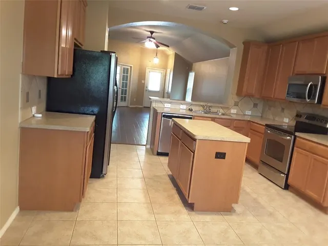 a kitchen with stainless steel appliances granite countertop a stove a sink and a refrigerator