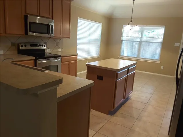 a kitchen with stainless steel appliances granite countertop a sink a stove a microwave and wooden cabinets