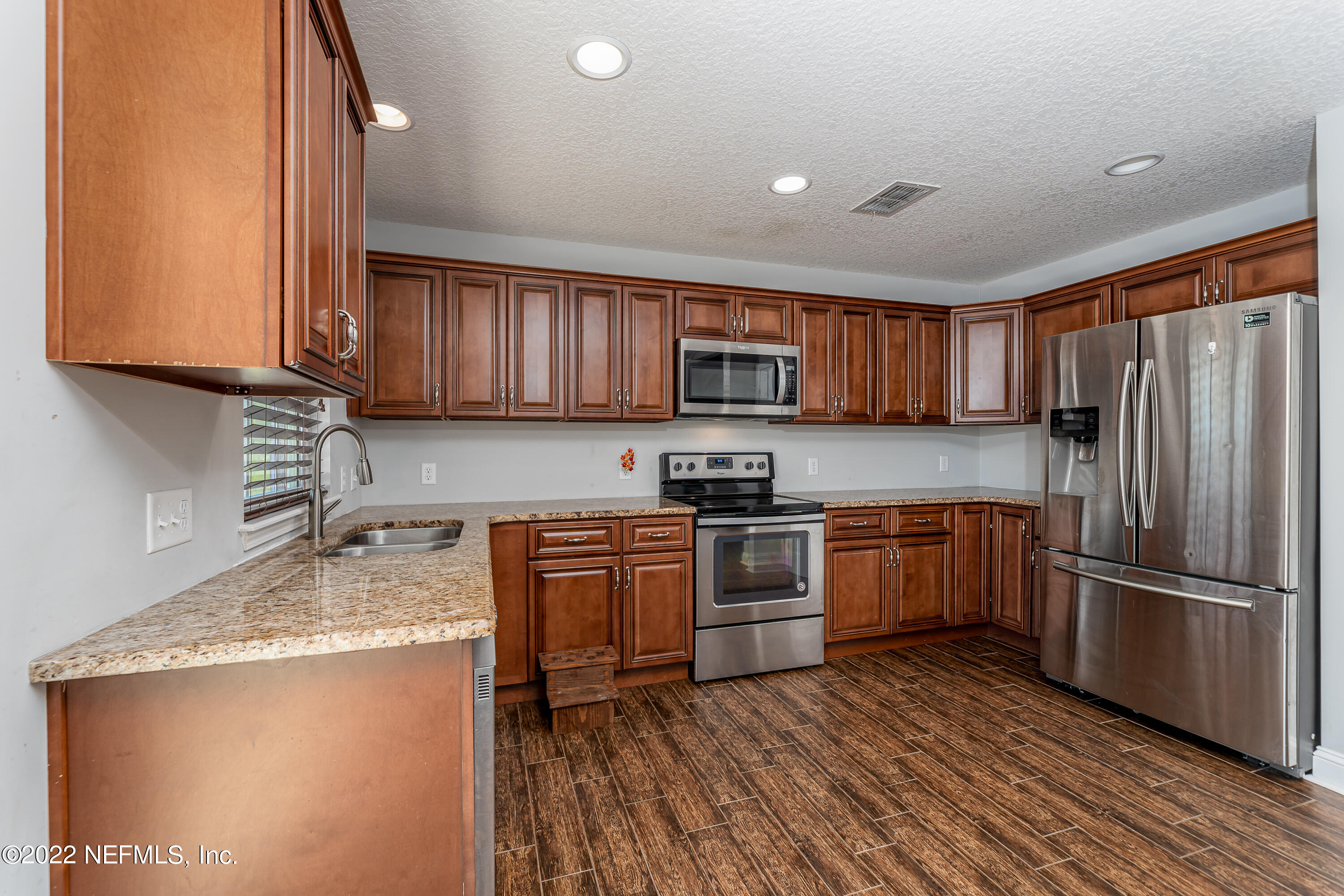 9143 McClelland Road Jacksonville, FL 32234 - Photo 11 of 37 a kitchen with granite countertop wooden cabinets a stove a oven and a refrigerator with wooden floor