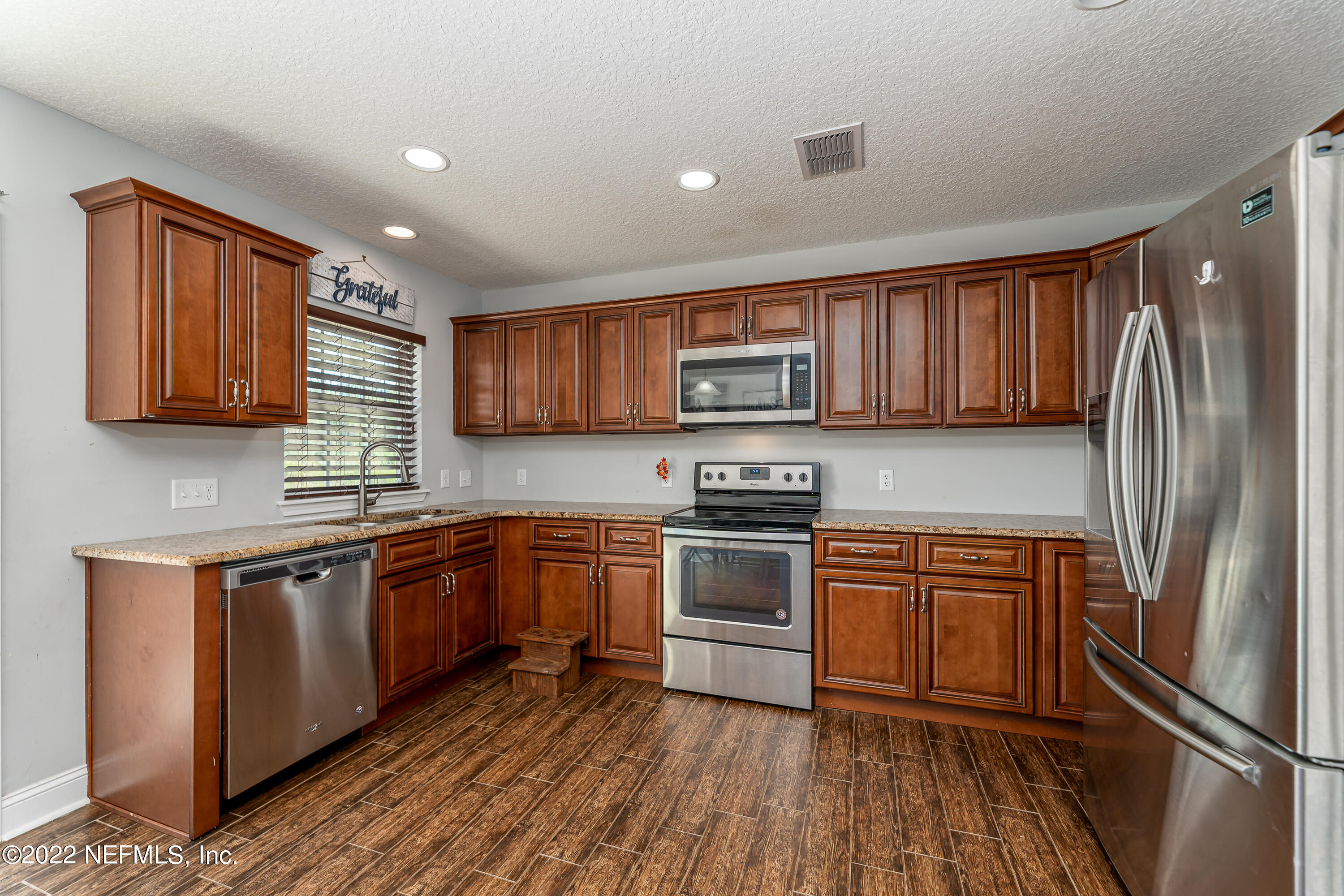 9143 McClelland Road Jacksonville, FL 32234 - Photo 12 of 37 a kitchen with stainless steel appliances granite countertop a refrigerator a stove top oven a sink and dishwasher with wooden floor