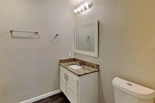 a bathroom with a granite countertop sink a toilet and mirror