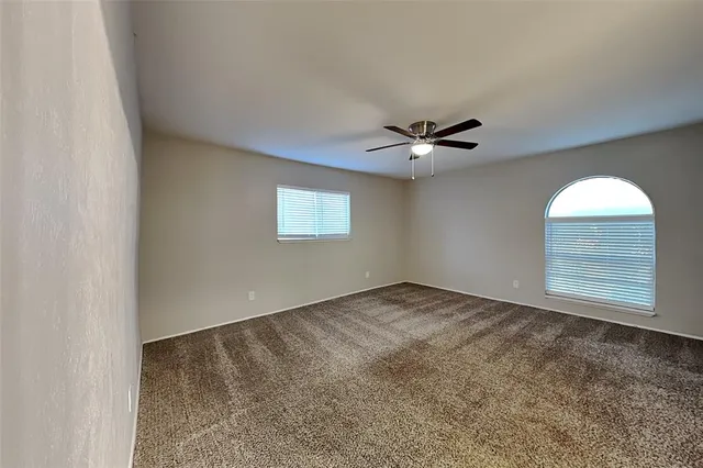 an empty room with a ceiling fan and window