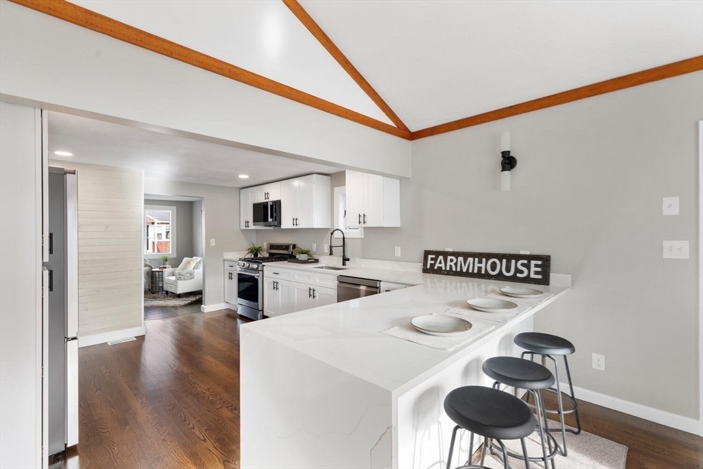 49 Butler Avenue Stoneham, MA 02180 - Photo 11 of 36 a kitchen with a sink a stove cabinets dining table and chairs
