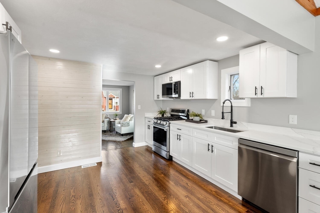 49 Butler Avenue Stoneham, MA 02180 - Photo 10 of 36 a kitchen with a sink dishwasher a stove and a refrigerator with wooden floor