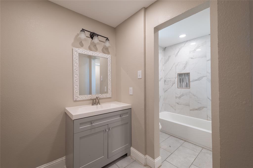 11005 Ferguson Road Dallas, TX 75228 - Photo 13 of 23 Bathroom vanity with a white countertop and a framed mirror, complemented by a three-light fixture