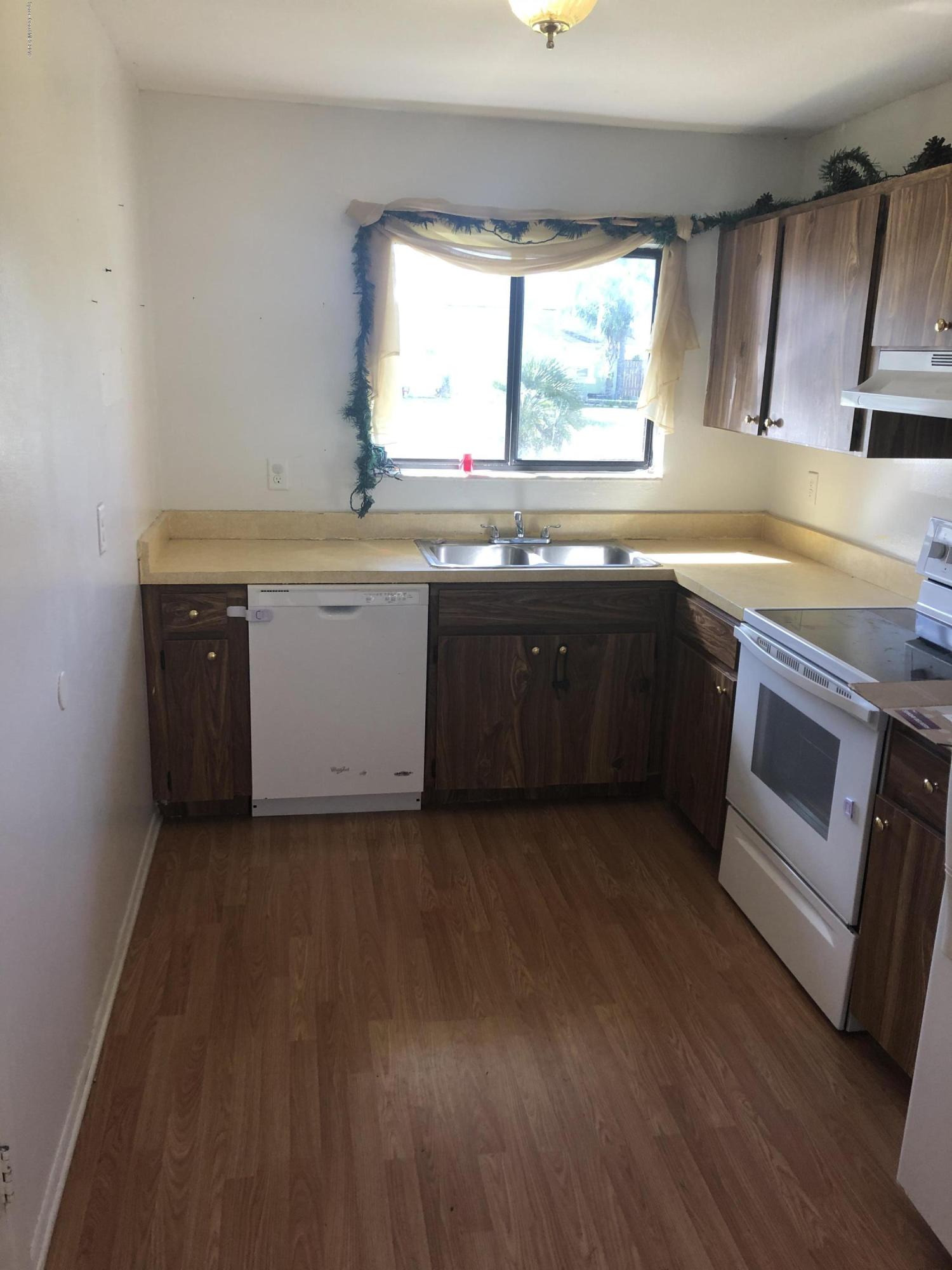 232 Abalone Road Northwest Palm Bay, FL 32907 - Photo 4 of 18 a kitchen with wooden cabinets and a sink