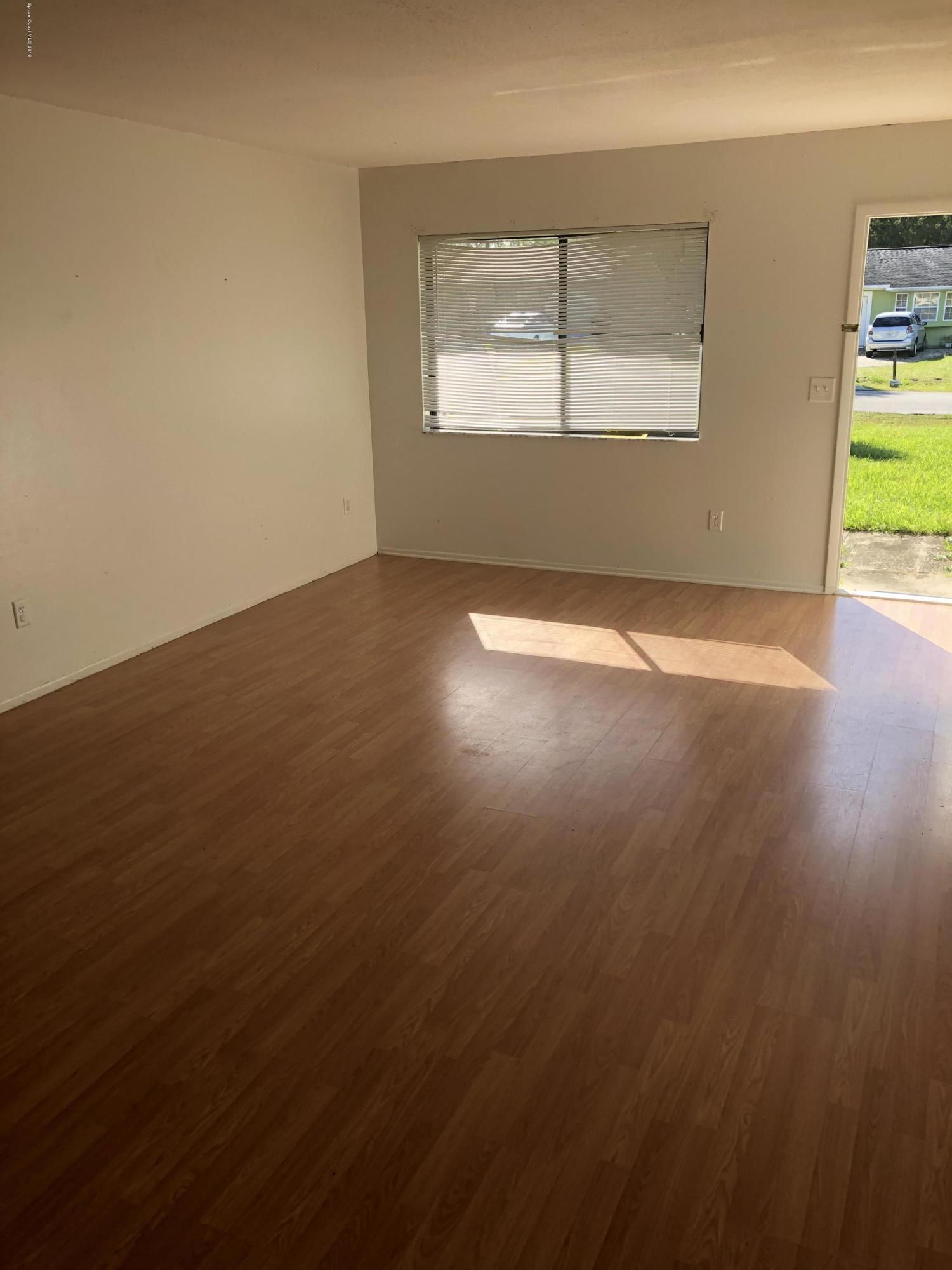 232 Abalone Road Northwest Palm Bay, FL 32907 - Photo 7 of 18 an empty room with wooden floor and windows