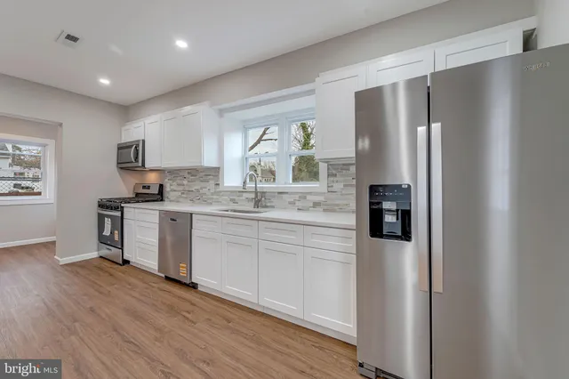 a kitchen with stainless steel appliances granite countertop a refrigerator and a stove top oven